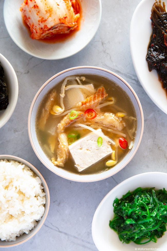 Close up photo of dried pollack soup served with various Korean side dishes and rice.