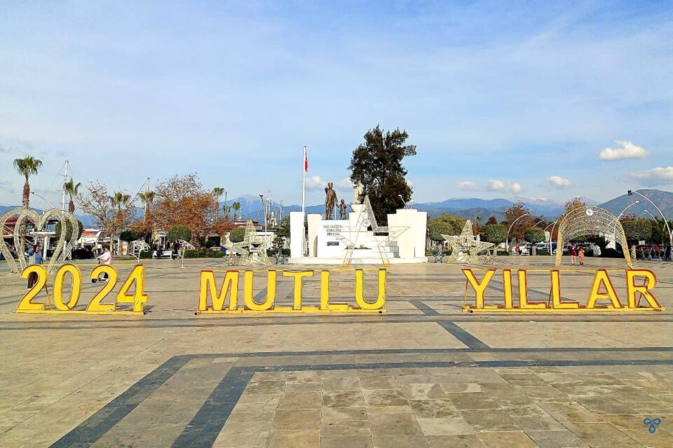 Happy new year written in Turkish in yellow letters in front of an Atatürk statue.