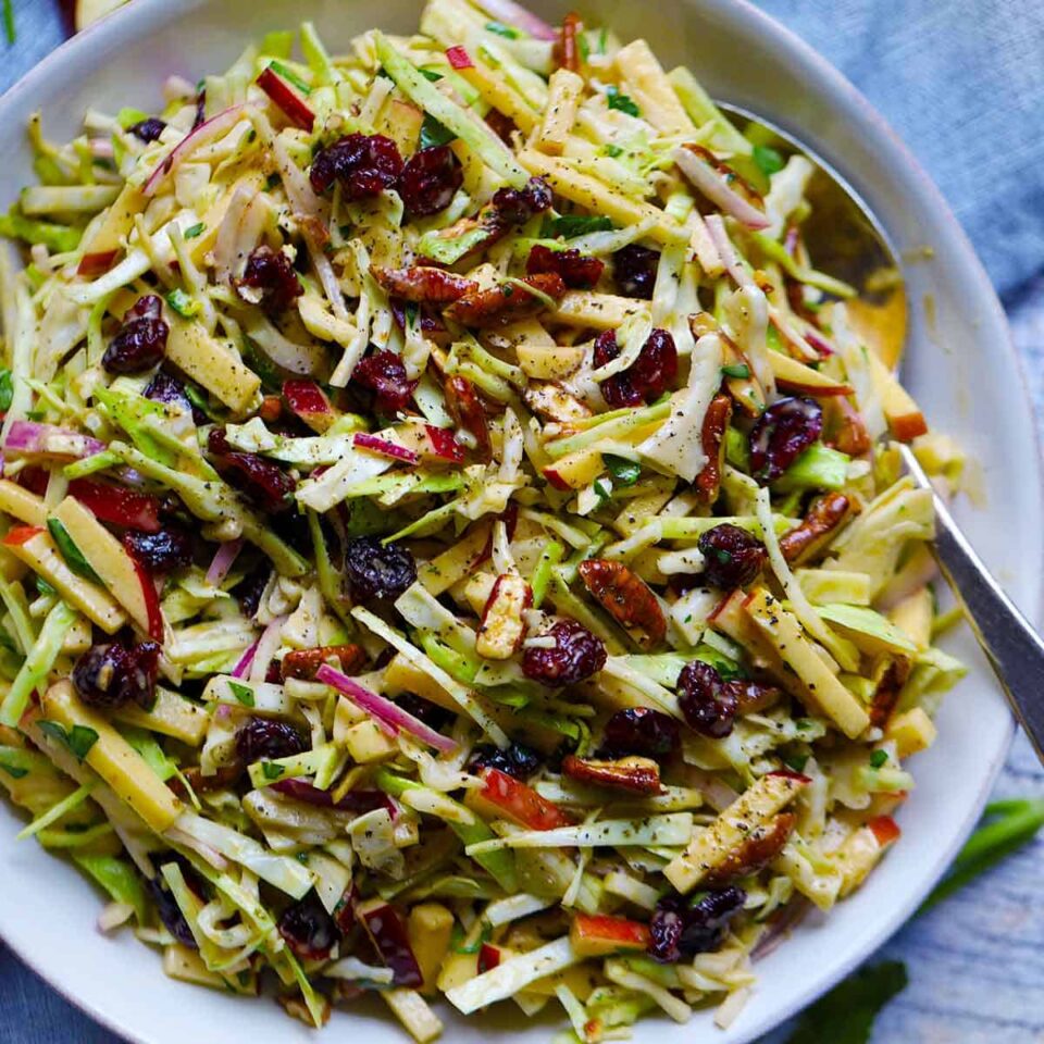 Square photo of apple slaw in a white bowl overhead.