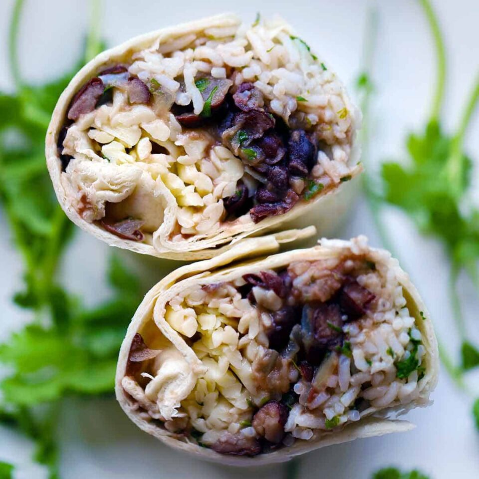 Square photo of freezer burritos with beans, rice, and cheese, cut cross-wise and standing up on end, and photo taken from above.