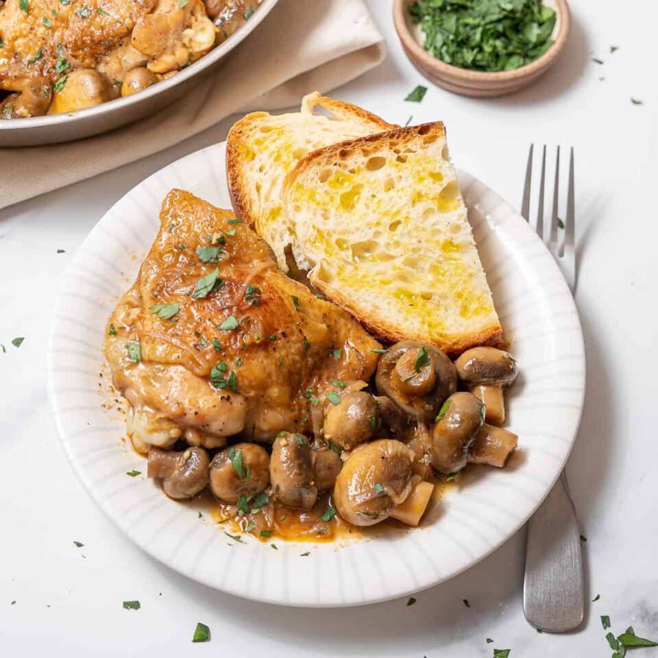 plate of chicken and mushrooms with sliced bread.