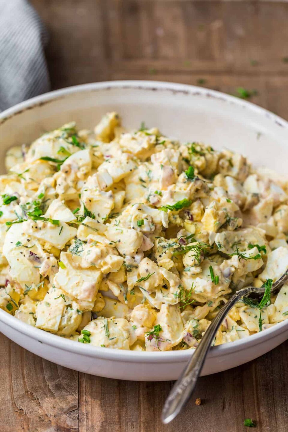 Quick Egg Salad in a serving bowl with a spoon and garnished with herbs,