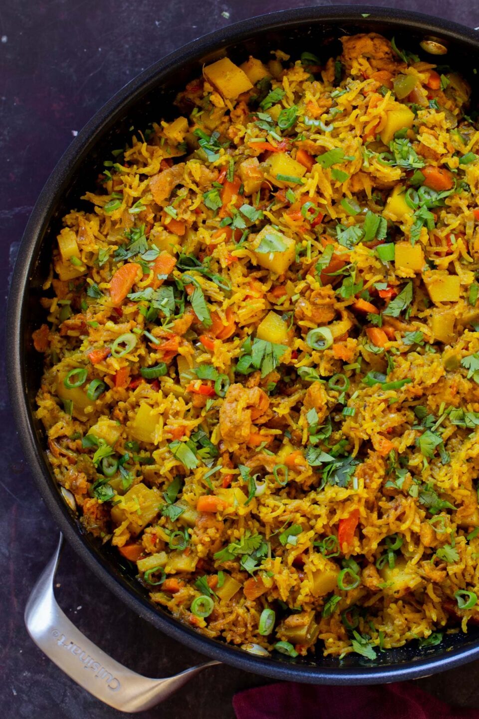 Jamaican curry rice in the pan with cilantro and green onions