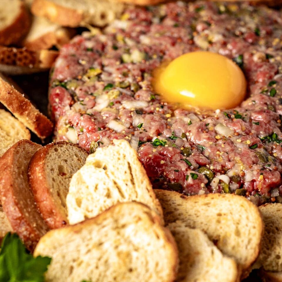 Steak tartare next to toasted rounds.