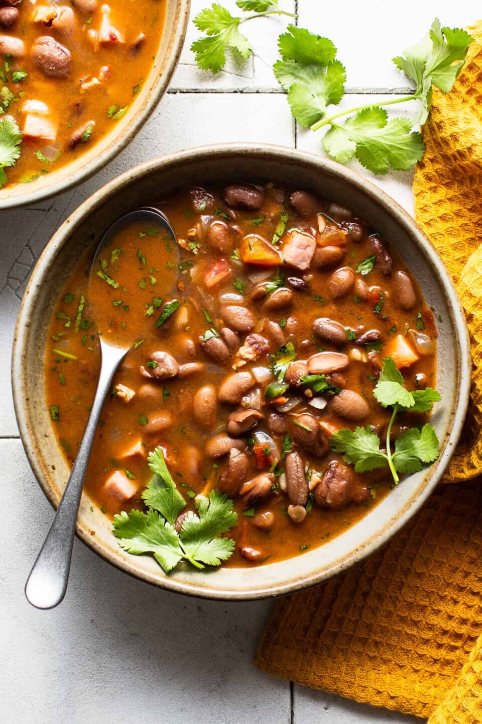 A bowl of charro beans topped with fresh cilantro on a table.