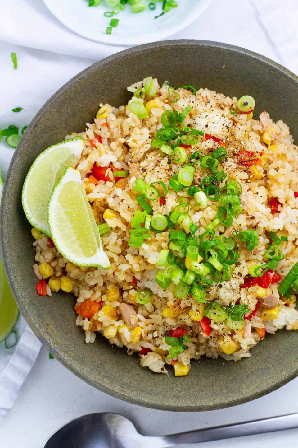 Top view of tuna fried rice with lime wedges on top.