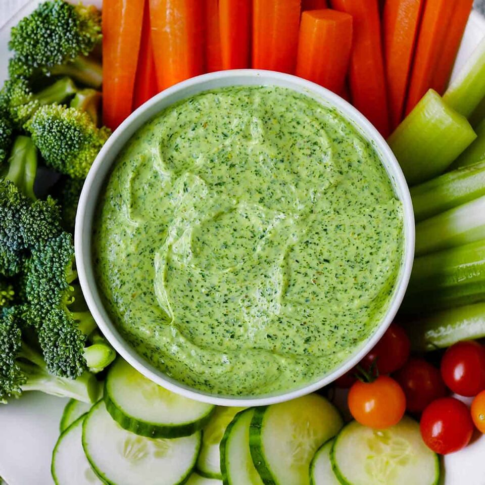 Square photo of Green Goddess dressing and veggies for dipping.