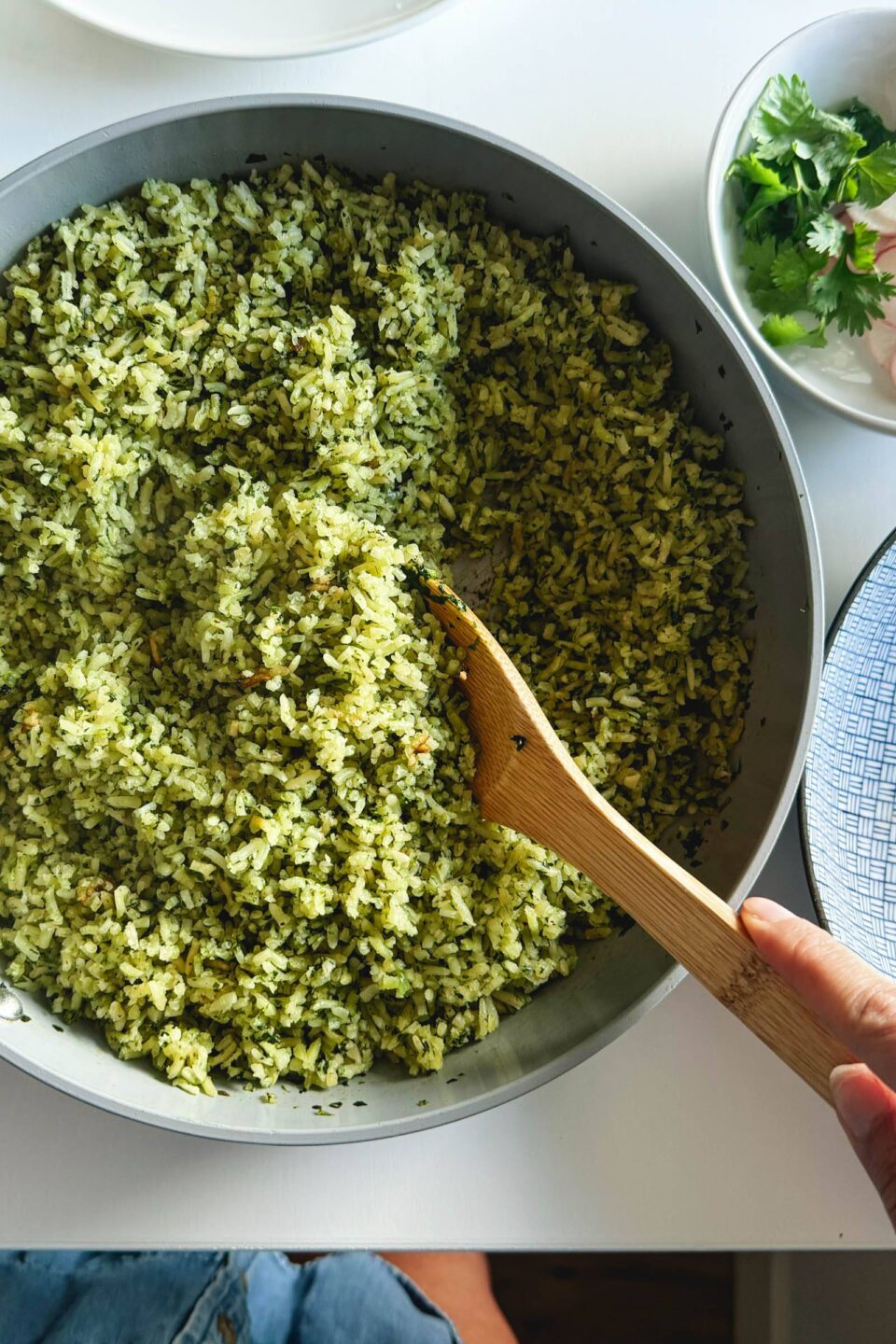 Cooked green rice in skillet with cilantro on the side