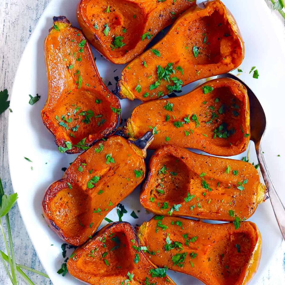 Square photo of a platter of halved roasted honeynut squash.