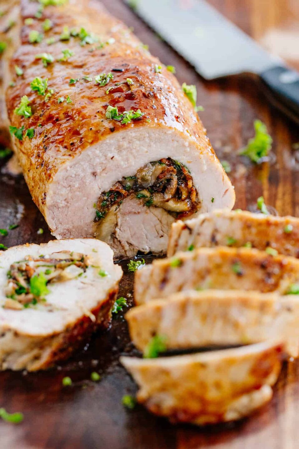 Stuffed pork tenderloin sliced on a cutting board