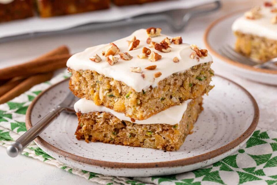 Close up of two pieces of pineapple zucchini cake stacked on a stoneware plate.